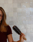 Person holding a brush against a tiled wall