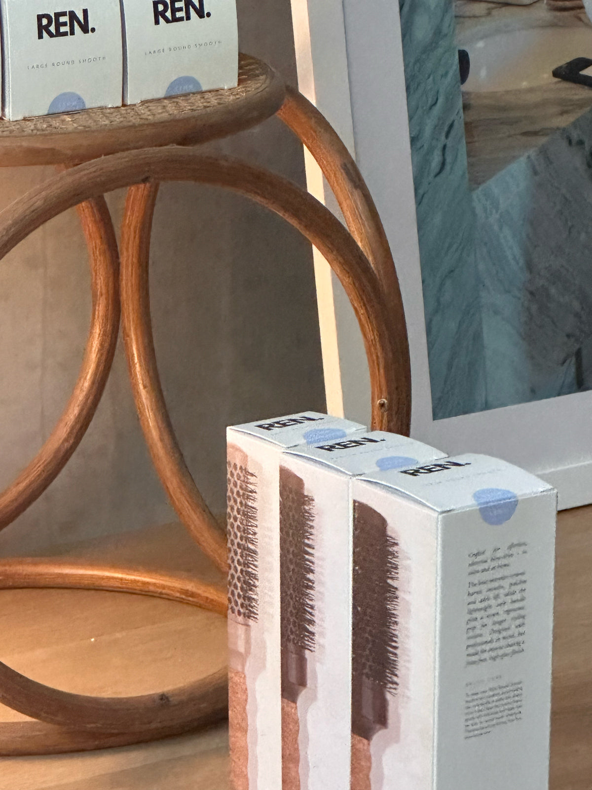 Two REN product boxes on a wooden surface with a blurred background