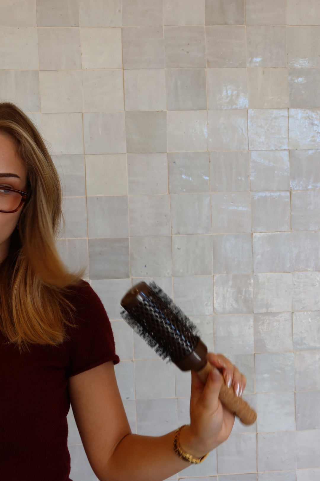 Person holding a brush against a tiled wall