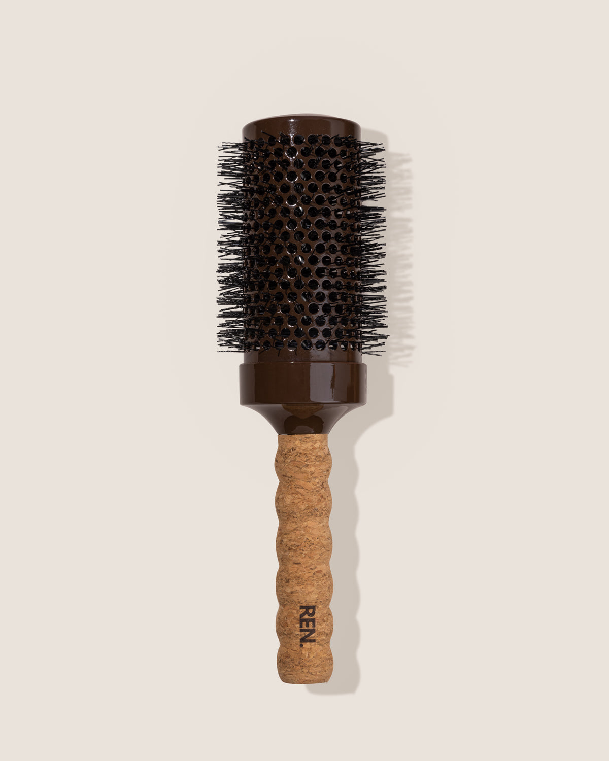 Hairbrush with cork handle and brown bristle head on a beige background