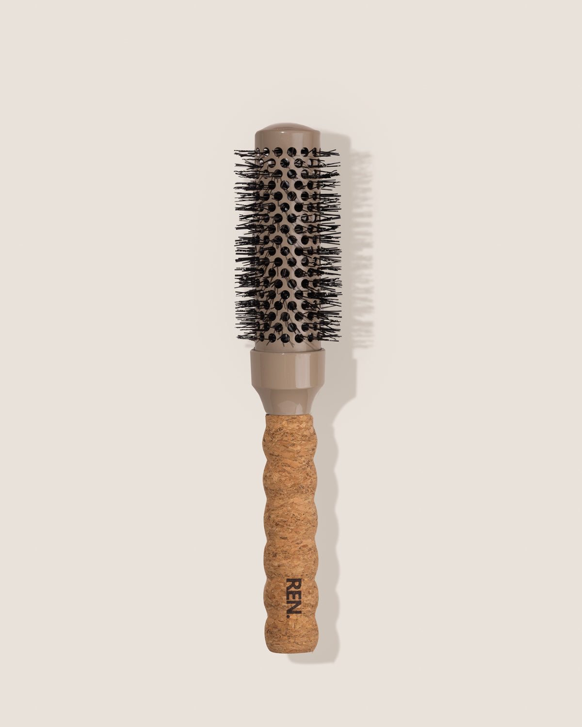 Hairbrush with cork handle and 'REN' branding on a beige background