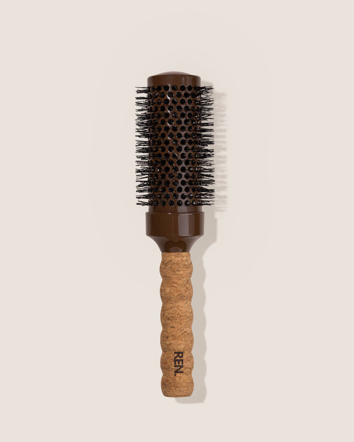 Hairbrush with cork handle and brown bristle head on a beige background